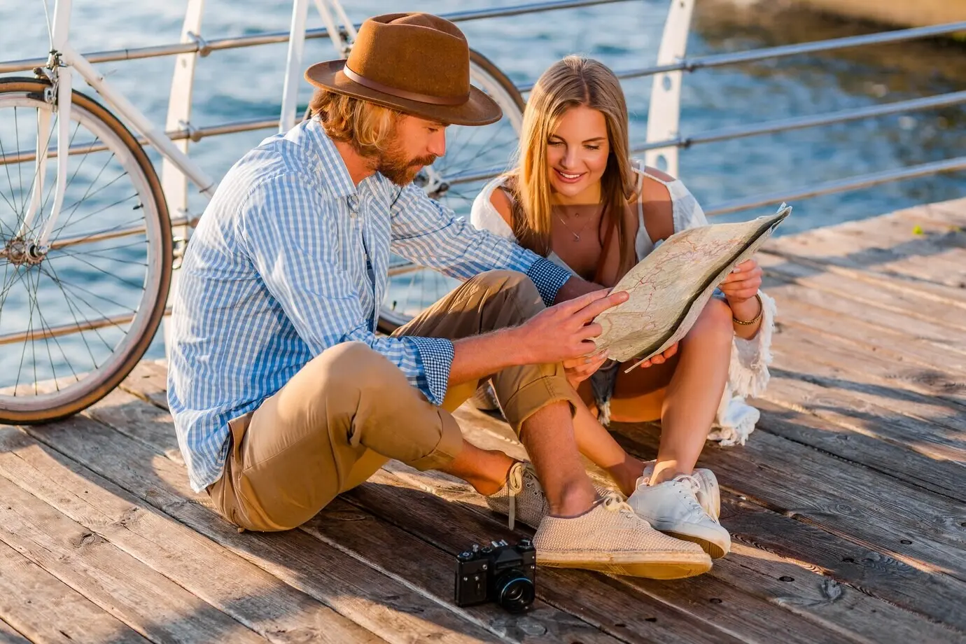 Eine Frau und ein Mann, die ineinander verliebt sind, sind bei Sonnenuntergang am Meer auf Fahrrädern unterwegs.